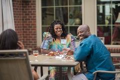 Three people are sitting at a table taking a photo